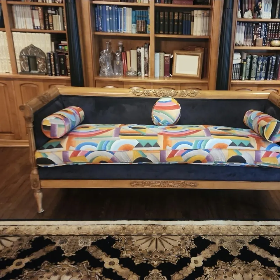 The same antique settee reupholstered in a colorful designer fabric with matching bolsters