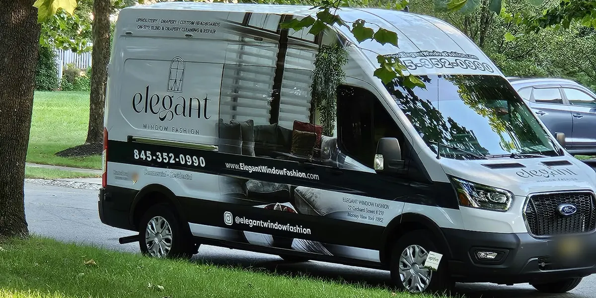 An Elegant Window Fashion van parked under the trees